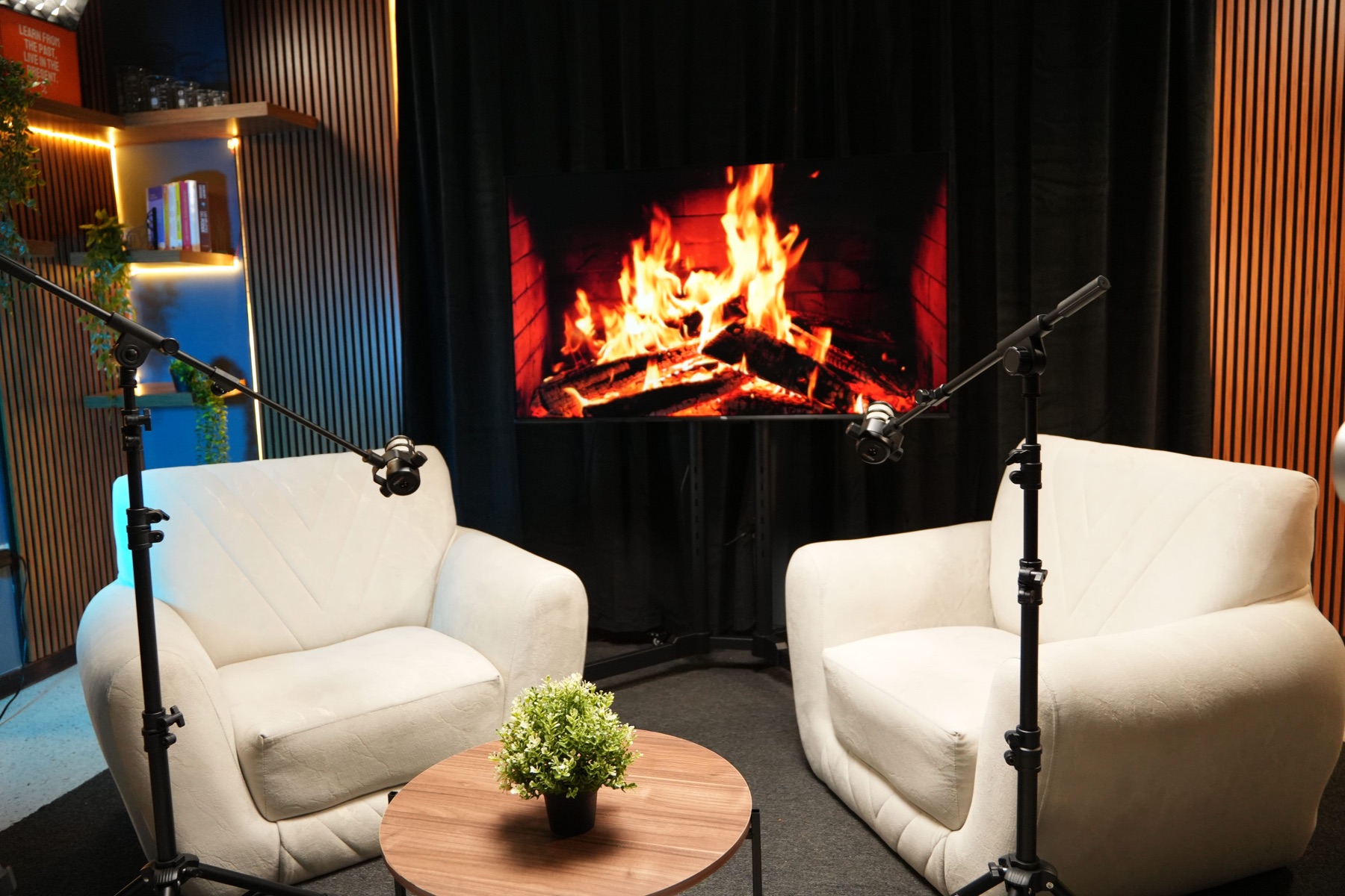 Set de podcast de DOSIS Creativa en Cali: dos sillones blancos con micrófonos de brazo frente a una pantalla encendida